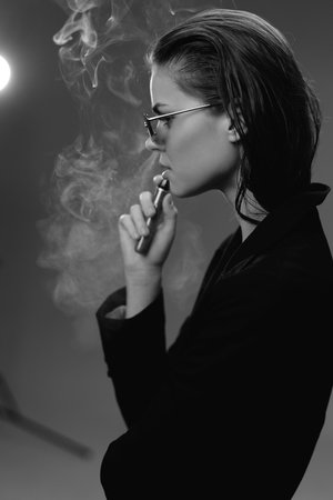 Black and white portrait of a woman smoking electronic cigarette, stylish and contemplative mood.