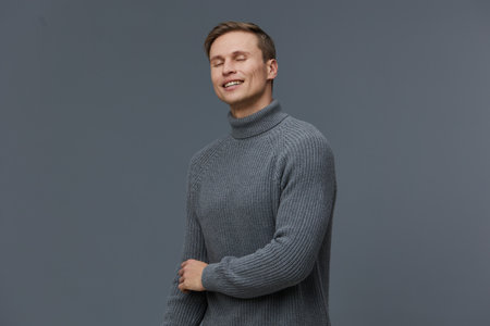 smiling man in gray knitted turtleneck enjoy digital detox close eyes relaxed casual wear plain gray...