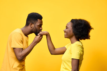 A joyful African couple wearing matching yellow t shirts enjoys a tender moment together, showcasing...