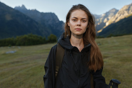 A confident traveler stands outdoors in a rugged mountain landscape, wearing a black jacket and...