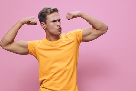 Young man showing strong muscles flexing biceps on pink background. Confidence, strength, fitness,...
