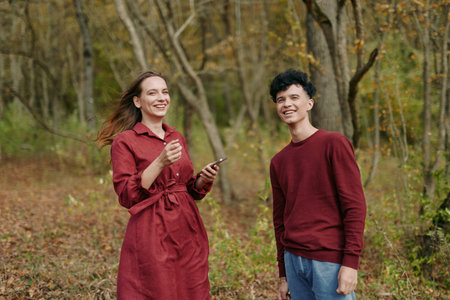 A candid autumn portrait of two friends smiling in a forest clearing, filmed with authenticity and...