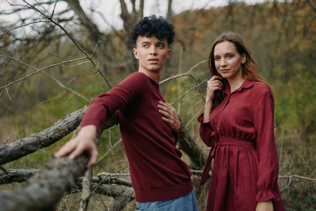 Young couple posing outdoors in a natural autumn landscape, relaxed and connected with genuine...