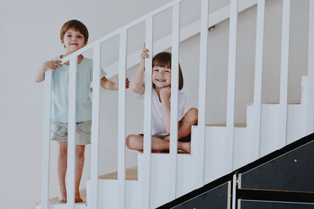 Playful children enjoying time on a staircase, smiling happily as they explore their surroundings with carefree joy and excitement.の写真素材