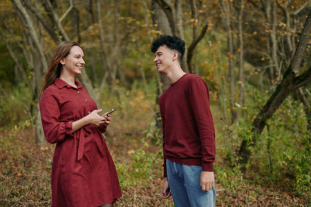 An authentic moment outdoors, a candid smile, natural light, warm autumn tones, and simple wardrobe, portraying a genuine connection and relaxed mood.の写真素材