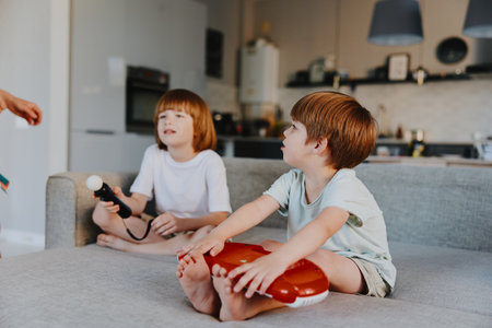 Two boys playing together in a bright living room, engaged in fun activities. Their laughter fills the space as they enjoy time with friends and toys.の写真素材