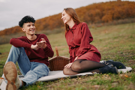 A candid outdoor portrait of a young couple sharing laughter during a picnic on a meadow, capturing authentic emotion and natural interaction that highlights genuine connection and relaxed chemistry.の写真素材