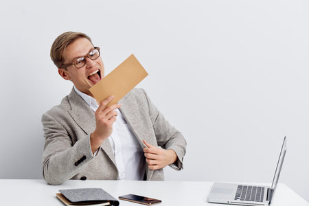 Professional young businessman in gray blazer and glasses holding a greeting card, expressing...