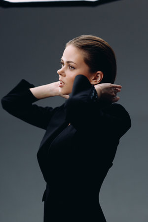 Profile of a thoughtful woman in a black outfit against a dark background, showcasing elegance and contemplative expression.の写真素材