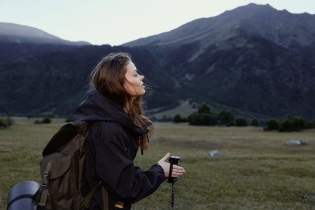 A female hiker with a backpack gazes across a vast mountain landscape, capturing a moment of...