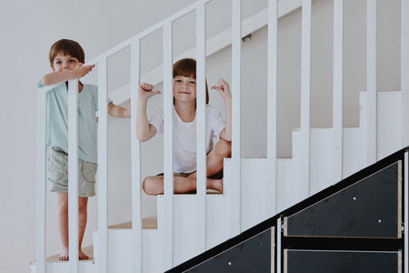 Two happy boys play on the staircase, showcasing their playful spirit with laughter and joy, emphasizing childhood innocence and exploration.の写真素材