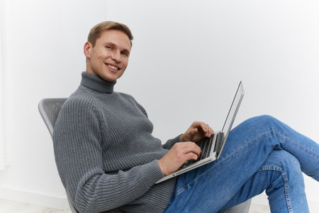 smiling man working on laptop wearing gray turtleneck sweater sit cozy chair casual outfit white...