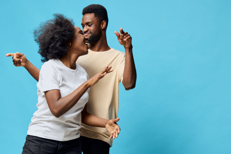 A joyful couple dancing together in front of a bright blue background, showcasing happiness and connection in a lighthearted momentの写真素材