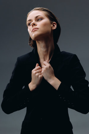 confident woman in black jacket looking up with determined expression and neat hairstyleの写真素材