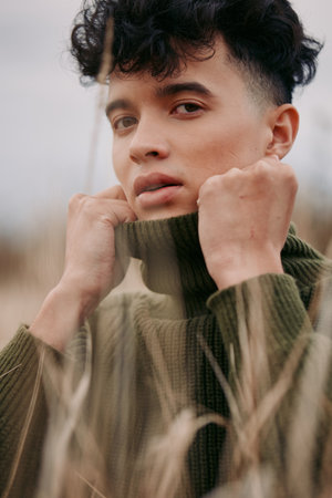 An authentic portrait of a youth in a cozy knit sweater, conveying honest emotion and credibility through natural light and an unposed, calm expression in a rural setting.の写真素材