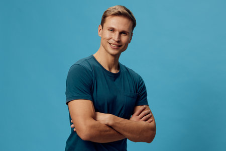 smiling caucasian man folded arms stand blue background casual t-shirt confident young adult digital...