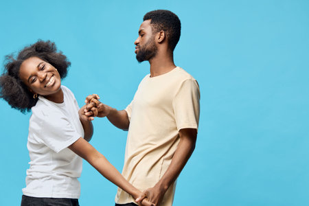 Happy African couple enjoying playful interaction against a bright blue background, showcasing joy, connection, and love in a contemporary settingの写真素材