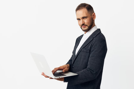 Business professional man stands with a laptop on an isolated white background, radiating...