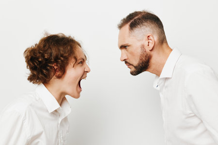 A tense business moment with a professional man facing another, displaying strong emotions against a colored isolated background. The scene emphasizes leadership, determination, and dynamicの写真素材