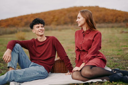 A candid scene emphasizes authenticity and credibility as a couple sits on a blanket in an autumn field, sharing a warm smile, quiet talk, and genuine connection.の写真素材