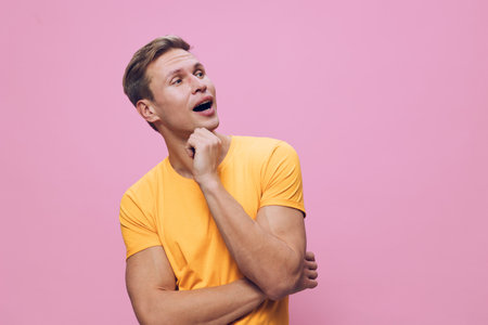 Young thoughtful caucasian man in yellow t-shirt look away isolated on pink background studio portrait digital detox conceptの写真素材