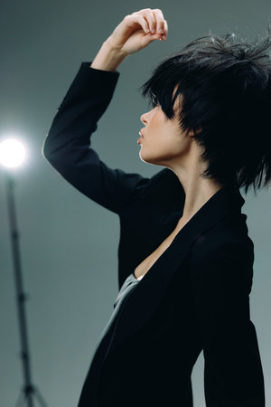 Profile of a stylish woman with short black hair posing against a dark background with studio lighting.の写真素材
