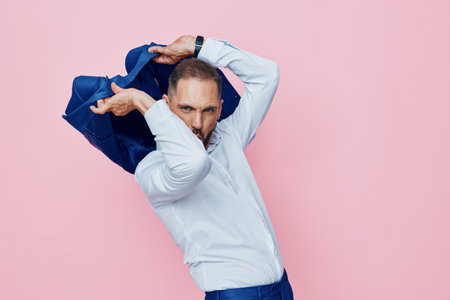 Professional businessman on a pink studio backdrop, posed with a dynamic gesture. Emotions of confidence and surprise convey determination and readiness for change in a bold, isolated color setting.の写真素材