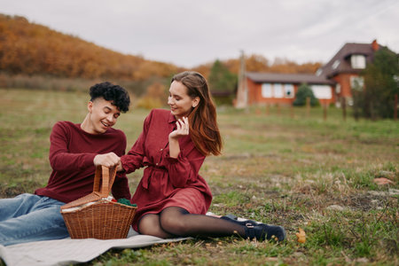 A candid moment of a couple picnicking in a sunlit field, radiating authenticity and warmth as they share a smile and simple joy on a relaxed afternoon.の写真素材