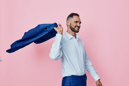 A confident business professional stands against a solid pink background, with a blue cape of fabric over his shoulder, symbolizing triumph and resilience.の写真素材