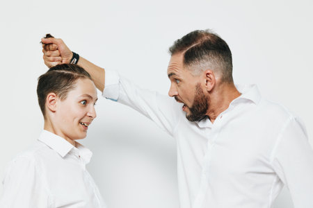 A professional business man interacts with a younger colleague showing playful intensity; he smiles...