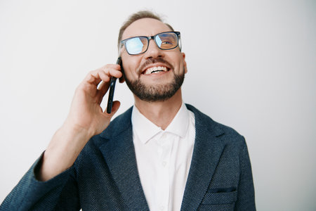 Professional business man on a call, smiling with confidence against an isolated colored background. The scene conveys optimism, focus, and approachability for corporate communication and leadershipの写真素材