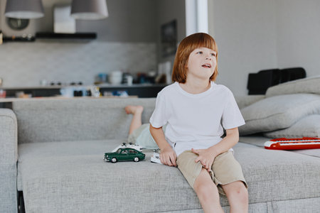 Happy boy playing with toy cars in a cozy living room, showcasing a playful atmosphere and warm...