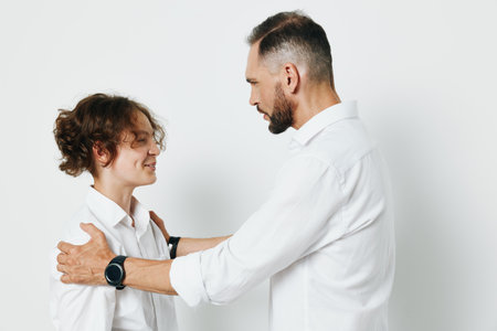 A professional man and colleague share a warm moment against a solid white background, conveying confidence, leadership, and supportive teamwork in a business setting.の写真素材