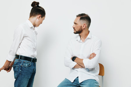 A composed business professional man stands with folded arms, engaging a colleague with a calm, focused expression against an isolated colored background.の写真素材