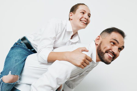 Professional man in business attire smiles while piggybacking a colleague, captured against an isolated white background. The scene conveys teamwork, confidence, and positive emotion for a dynamic,の写真素材