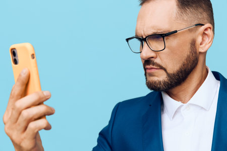 A focused business professional man stands against a vibrant colored background, expressing confidence, determination, and calm focus as he reviews notes on his smartphone.の写真素材