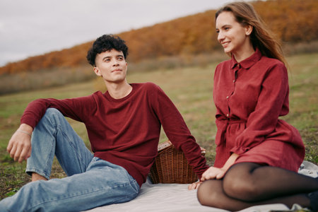 Authenticity and credibility frame a candid moment in an autumn field, where a relaxed couple shares a quiet scene in warm tones, simple outfits, and genuine ease.の写真素材