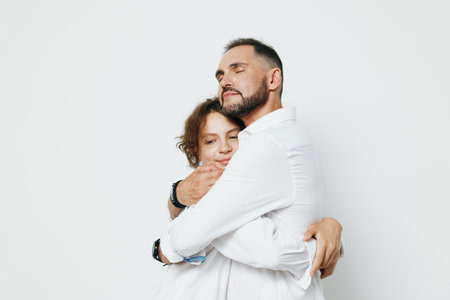 A professional man embraces a colleague in a warm moment on a clean bright backdrop, conveying emotion, support, and teamwork.の写真素材