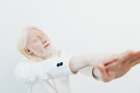 Man with long blonde hair in white suit reaching out, soft expression, minimalistic design with white background, conveying a sense of peace and tranquility, ideal for wellness themesの写真素材