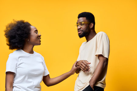 Happy young couple enjoying each other s company, dressed in casual clothes against a bright yellow...