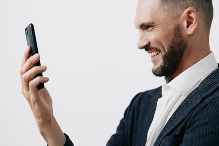 Professional man on a colored background, exuding confidence and focus, smiling softly at a phone, conveying emotion, ambition, and success in a modern business scene.の写真素材