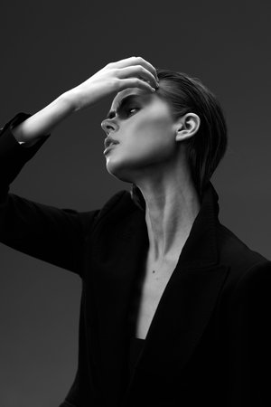 Black and white portrait of a thoughtful woman in stylish blazer with dramatic lighting and elegant poseの写真素材