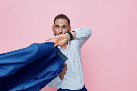 Professional man in a white shirt pulls a blue jacket across a bold pink background, conveying confidence, determination, and a moment of surprise in a corporate scene.の写真素材