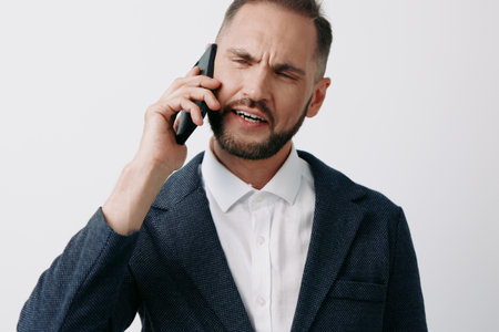 A professional businessman on a call, showing a tense and focused expression, isolated on a clean background. The scene conveys urgency, decision making, and communication under pressure.の写真素材