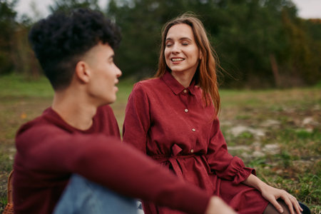 Young couple share a candid outdoor moment with genuine smiles and relaxed posture, capturing authenticity and credibility in a simple everyday connection bathed in soft natural light.の写真素材