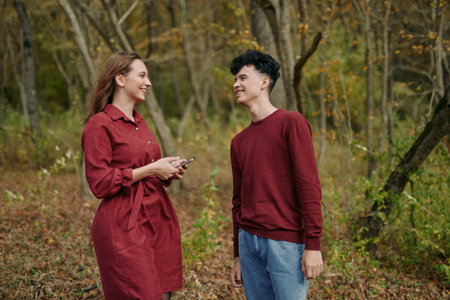 Authentic candid moment captures genuine interaction between two people sharing a smile in a natural autumn setting, conveying trust and sincerity in everyday connection and presence.の写真素材