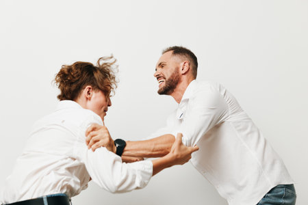 Theme: business man professional emotion. A dynamic pair of men in white shirts interact with energy against an isolated white background, conveying focus, determination, and confident teamwork.の写真素材