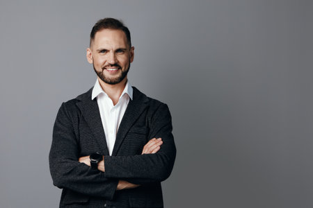 A confident business professional man stands with arms crossed, showing warm emotions against a solid colored background, conveying leadership, focus, and determination in a corporate setting.の写真素材