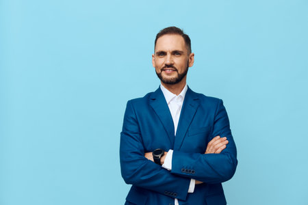 A confident business professional stands with arms crossed against a solid blue backdrop, exuding poise, focus, and readiness for leadership.の写真素材