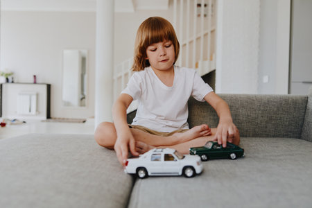 Young boy playing with toy cars in a cozy living room. The scene radiates joy, creativity, and a sense of childhood wonder.の写真素材